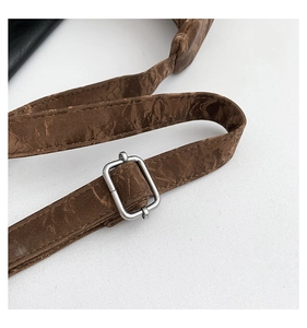 Macro shot of dark brown wrinkled texture shoulder strap with silver metal buckle