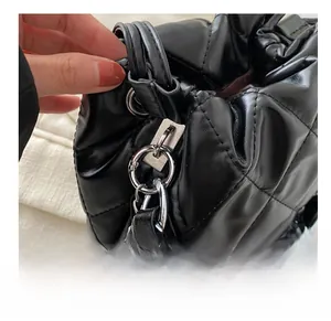Close-up of black quilted bucket bag featuring silver chain strap and metal hardware details