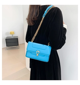 Détail d'un sac bandoulière bleu vif avec boucle dorée en U sur une robe noire