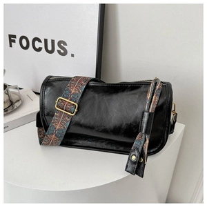 Détail du sac cylindre noir en cuir brillant avec large bandoulière brodée colorée