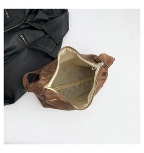 Detail view of brown pleated shoulder bag with metallic zipper and spacious interior