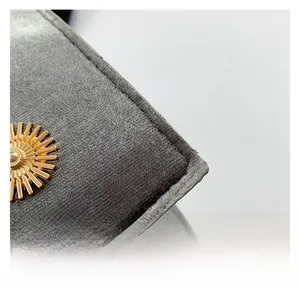 Détail de la texture velours gris avec boucle métallique soleil doré sur le sac à main