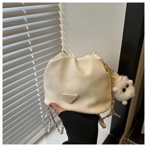 Detail of cream bucket bag with drawstring closure and metal triangle logo on soft leather