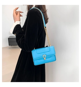 Détail du sac bandoulière en cuir bleu vif avec chaîne dorée et fermoir en métal