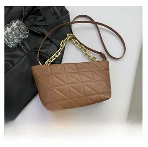 Detailed view of brown quilted leather handbag with gold chain handle and shoulder strap