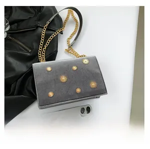 Vue à plat d'un sac en velours gris avec clous dorés soleil et bandoulière chaîne
