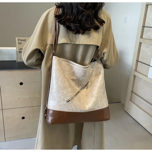 Detail of a large color-block tote bag in cream and brown with diagonal zipper accents