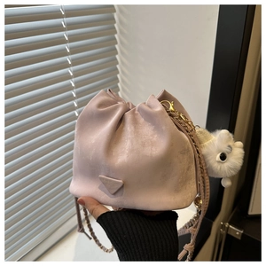 Detail of light purple soft bucket bag with gold chain and plush toy charm in natural light