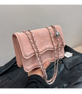 Detail of pink velvet flap bag with wavy edges and silver chain strap with ball charm