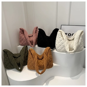 Detailed display of corduroy quilted tote bags in five different colors on pedestals