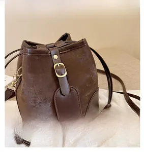 Detail showing the coffee brown bucket bag with gold pin buckle and drawstring closure