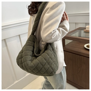 Close-up of olive green quilted corduroy hobo bag with diamond pattern worn by model
