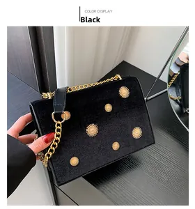 Détail du sac en velours noir avec des ornements de marguerites dorées et bandoulière chaîne