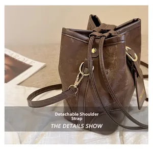 Detail of dark brown bucket bag featuring gold hardware and detachable shoulder strap