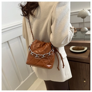Detail of caramel brown quilted bucket bag with silver chain and Fashion & Bags text