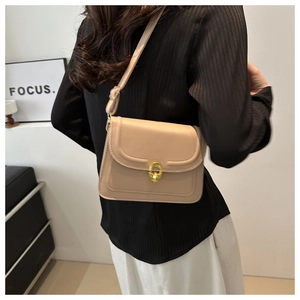 Minimalist beige leather shoulder bag with gold ring buckle shown on a model
