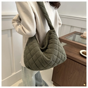 Detailed shot of dark green corduroy quilted crossbody tote bag worn by a model