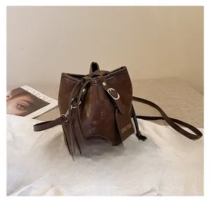 Detail view of deep brown bucket bag with drawstring and vintage textured faux leather