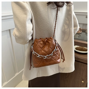 Detail of a brown quilted bucket bag with chain strap and drawstring closure