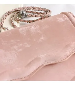 Detail of pink velvet crossbody bag with silver metal chain and adjustable ball buckle