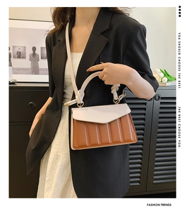 Detail of color-block satchel with cream flap and brown accordion pleat structure