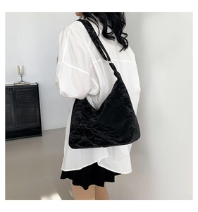 Detail view of black oversized tote bag with wrinkled texture and silver metal rings