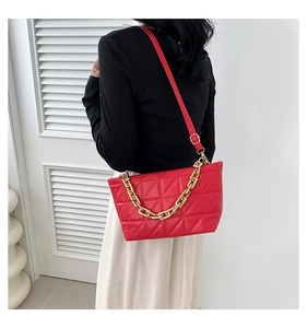 Detail view of red quilted crossbody bag with gold chain and adjustable strap on model