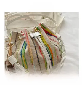 Detail view of beige canvas bucket bag featuring vertical stripes and cute bear pendant