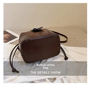 Detail view of the deep brown leather bucket bag bottom with drawstrings and shoulder strap