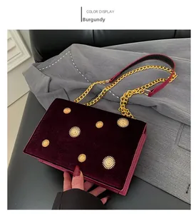 Détail du sac bandoulière en velours bordeaux avec des rivets métalliques tournesols