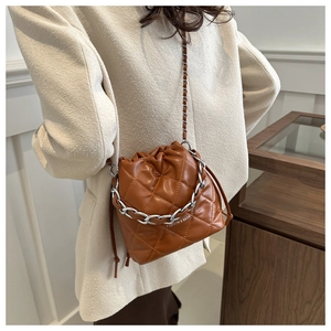 Brown quilted bucket bag with silver chain strap shown in a lifestyle street style photo