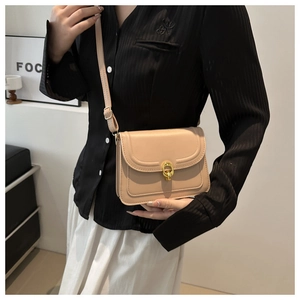 Minimalist beige crossbody square bag with golden buckle shown on shoulder with slim strap