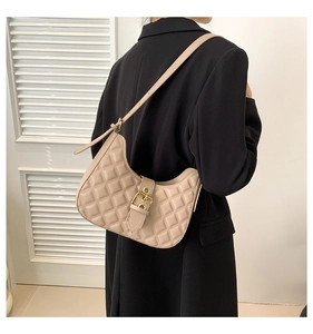 Sac hobo beige matelassé sur mannequin en blazer noir sur fond minimaliste épuré