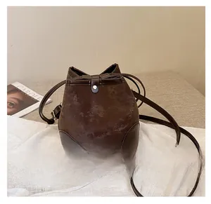 Detail of a dark brown bucket bag with marble texture and leather trim on white cloth