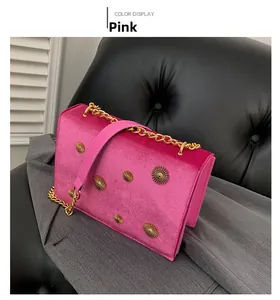 Détail du sac bandoulière en velours rose avec rivets dorés et bandoulière chaîne