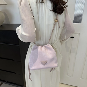 Pink faux suede bucket bag with drawstring closure and elegant gold chain strap