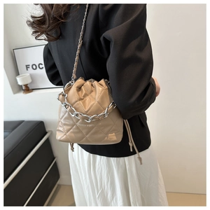 Close-up of khaki quilted bucket bag featuring silver chain detail and drawstring closure