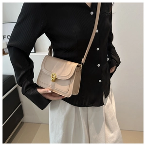 Detail of minimalist beige crossbody bag with gold-tone interlocking circular ring clasp