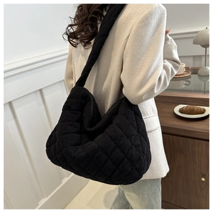 Quilted black corduroy hobo bag with wide shoulder strap shown in a lifestyle setting