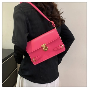 Pink faux leather crossbody bag with gold buckle shown on a model from the back