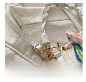 Detail of adjustable white leather strap and gold buckle on a pleated bucket bag