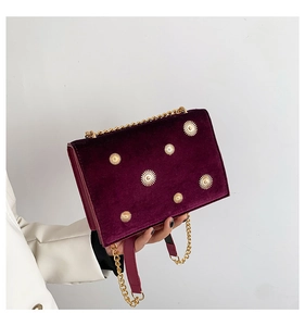 Détails du sac en velours bordeaux avec clous dorés motif soleil et bandoulière chaîne