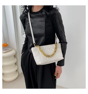 Detail of white quilted crossbody bag featuring a chunky gold chain handle and PU leather