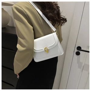 White minimalist shoulder bag with gold metal buckle worn with a stylish blazer