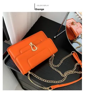 Détail macro du sac en cuir PU orange avec gaufrage en H et boucle fer à cheval dorée