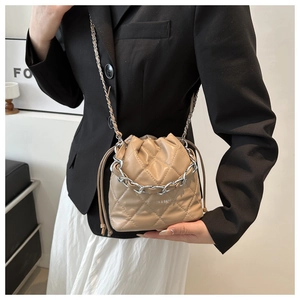 Detail of beige quilted bucket bag with silver chain strap and drawstrings