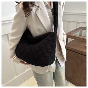 Quilted corduroy shoulder bag in black, showing side view and soft texture on model