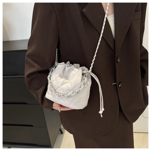 Detail of beige quilted bucket bag with silver chain strap and drawstring closure