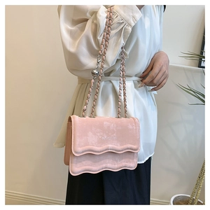 Detailed view of pink velvet crossbody bag featuring wavy edges and metal chain strap