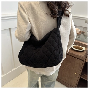 Detail showing the black quilted corduroy hobo bag worn by a model in a casual setting